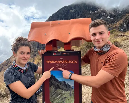 Happy couple pointing at the sign at Warmi Wañusca.