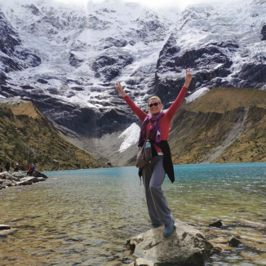 Beautiful tourist raising her arms at Humantay Lake.