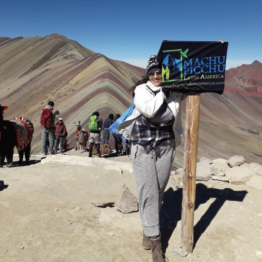 Beautiful young woman showing the Machupicchu Latin America banner at Vinicunca Rainbow Mountain.